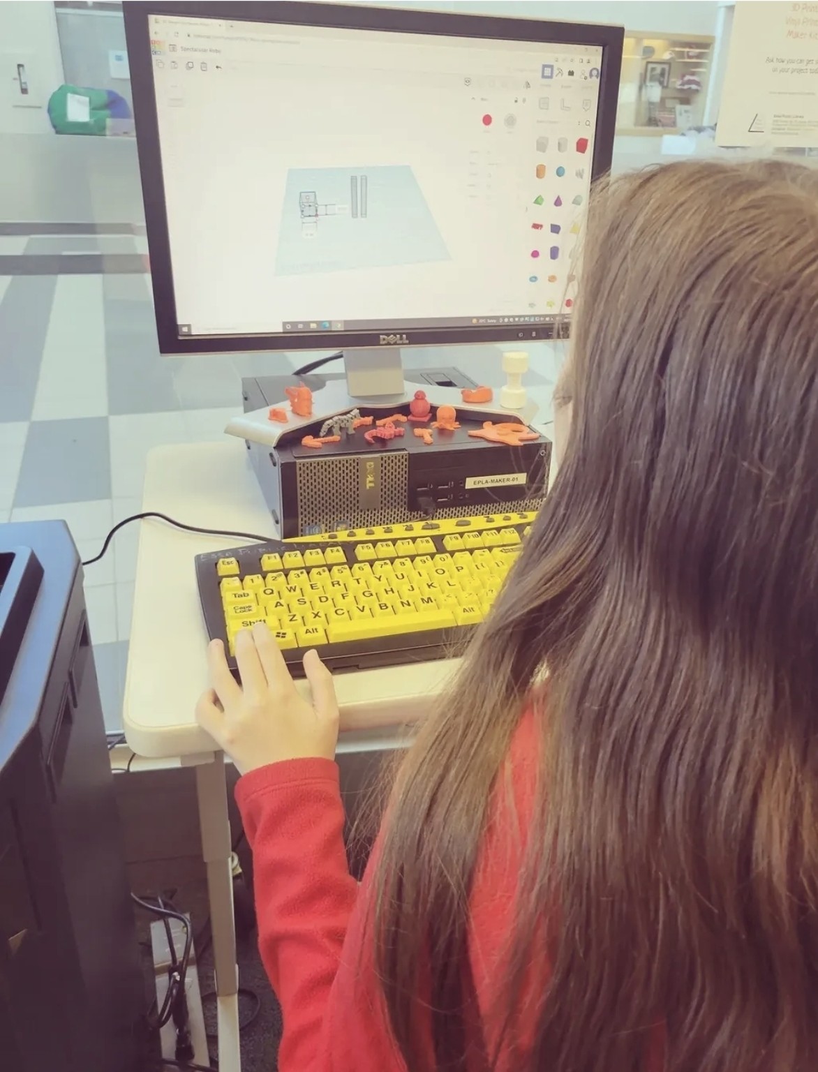 A Buddy UP! participant exploring a digital design beside colourful three-dimensional creations